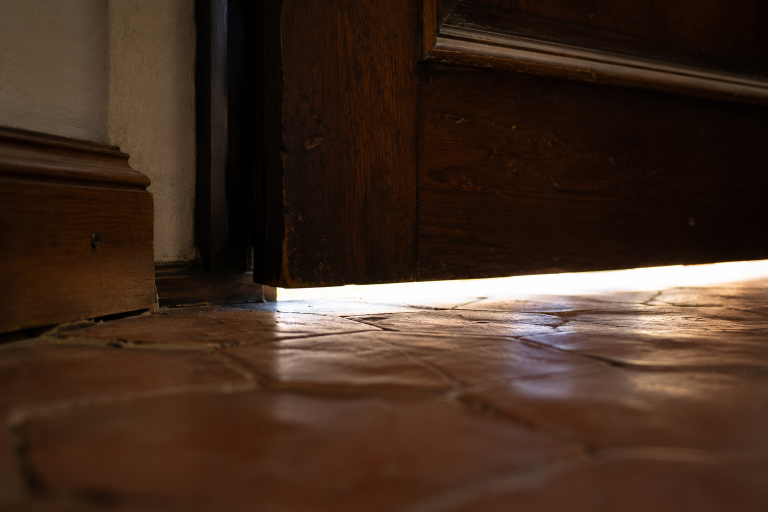 Jour de un à deux centimètres sous une porte d'entrée, vu de l'intérieur